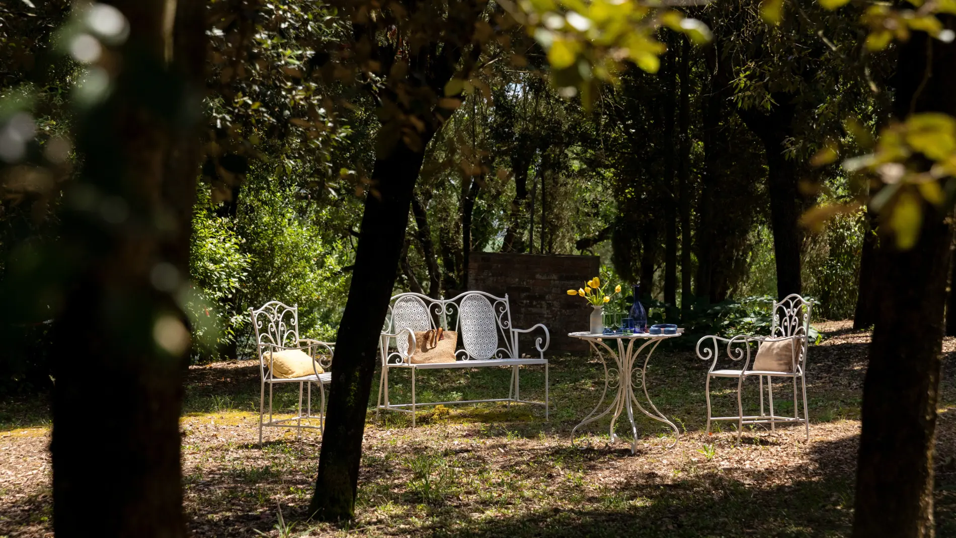 Garden lounge with wrought-iron seating among the trees - Villa San Bartolomeo, BZAR hotels in Tuscany