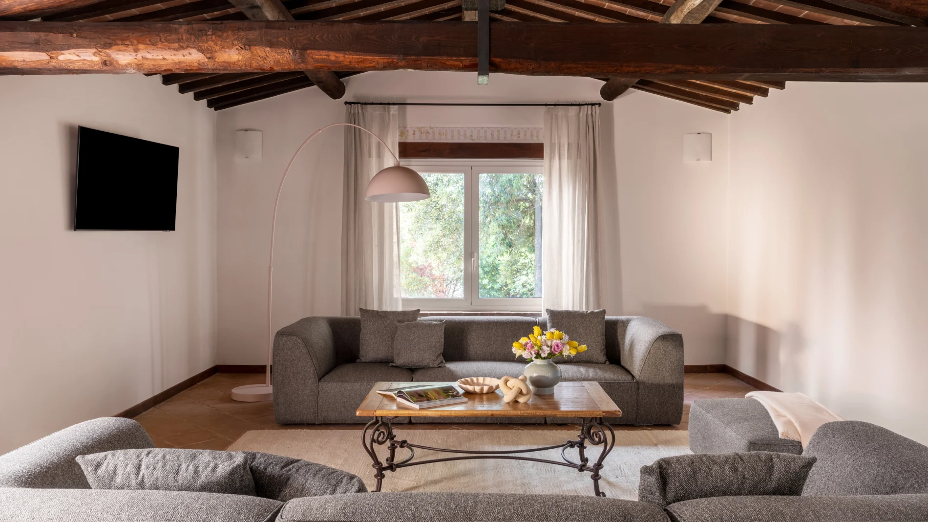 Spacious living room with grey sofas, exposed beams and TV - Villa San Bartolomeo, BZAR hotels in Tuscany